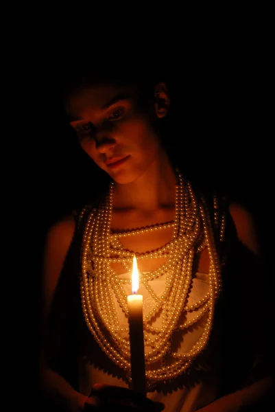 Menina com vela acesa na escuridão — Fotografia de Stock
