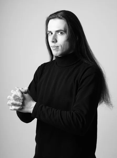 Wachsamer junger Mann mit langen Haaren in schwarz — Stockfoto