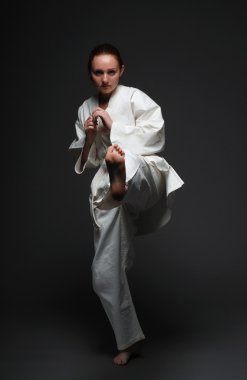 Girl in white kimono kicks forward left leg clipart