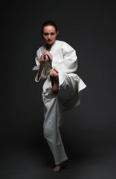 stock image Girl in white kimono kicks forward left leg