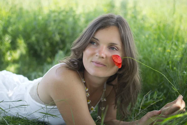 ポピーと草原に横たわっている美しい若い女性 — ストック写真