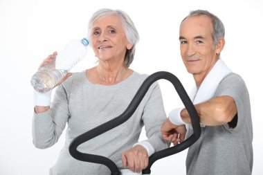 Elderly couple working out together in gym clipart