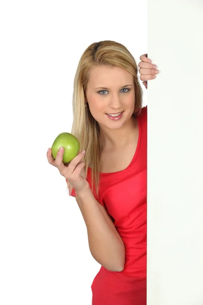 Женщина за белой панелью держит яблоко — стоковое фото