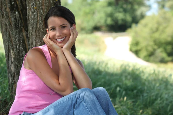 Portrait of lovely young brunette posing in park with face in her hands — Stock Photo, Image