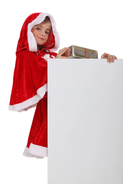 Menina em uma roupa de Papai Noel com uma placa deixou em branco para sua mensagem — Fotografia de Stock