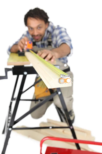 Carpinteiro medindo um pedaço de madeira — Fotografia de Stock
