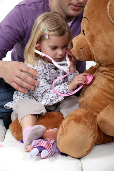 Young girl listening to her teddy's heartbeat — Stock Photo, Image