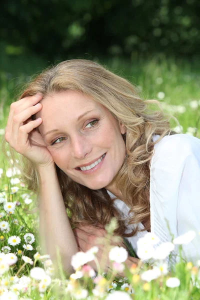 Blond woman laying in a field of daisies — Stock Photo, Image
