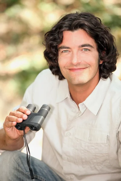 Un hombre sonriente con un par de binoculares — Foto de Stock