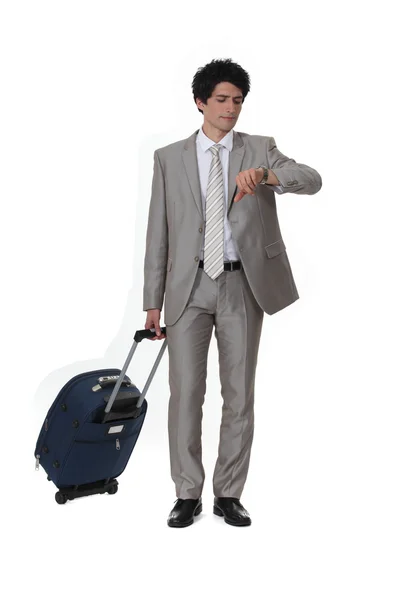 Бизнесмен с чемоданом смотрит на часы — стоковое фото
