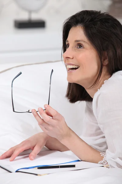 Woman writing in bed — Stock Photo, Image