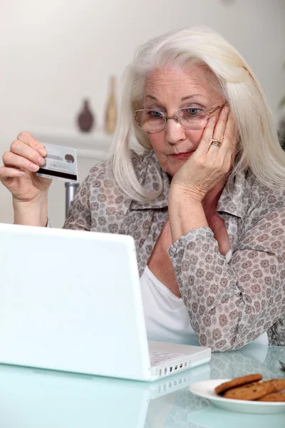 Mulher velha com cartão de crédito e computador — Fotografia de Stock
