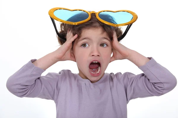Little girl screaming with huge funny sunglasses on head — Stock Photo, Image