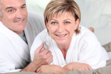 Mature couple in bed with bathrobe clipart