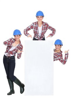 Female builder stood with blank poster clipart