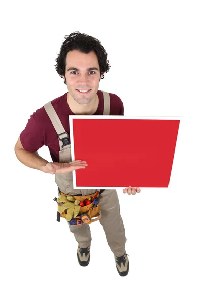 Handwerker gestikuliert auf leeres Plakat zu — Stockfoto