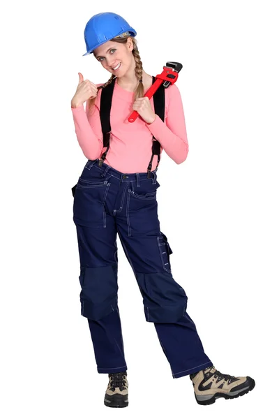 Tradeswoman giving the thumb's up and holding a pipe wrench — Stock Photo, Image