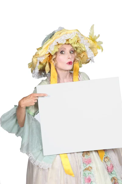 Verkleidete Frau zeigt auf leere Anzeigetafel — Stockfoto