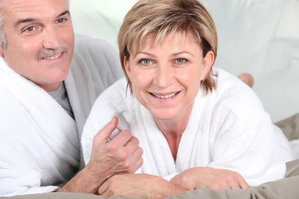 Mature couple in bed with bathrobe — Stock Photo, Image
