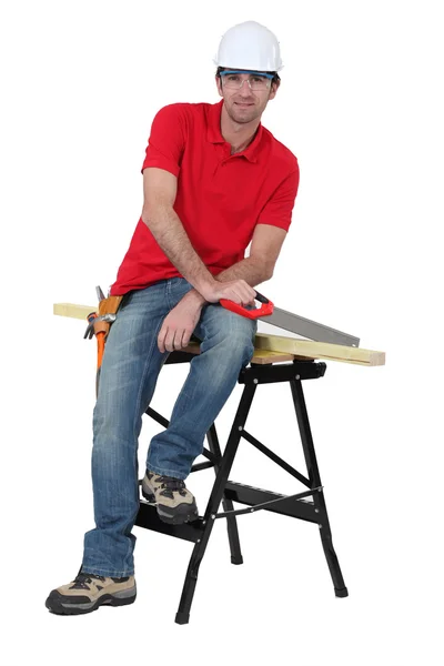 Man with a saw sitting on a workbench — Stock Photo, Image