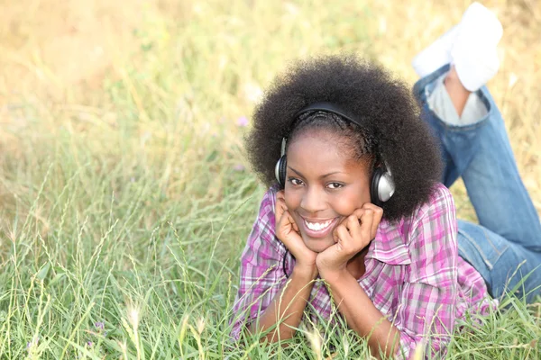 Chica acostada en la hierba con auriculares — Foto de Stock