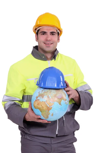 Trabalhador colocando um capacete em um globo — Fotografia de Stock