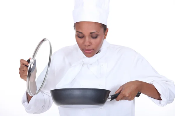 Vrouwelijke chef-kok op zoek in een pan van voedsel — Stockfoto