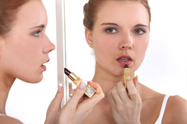 Mujer aplicando lápiz labial en el espejo — Foto de Stock