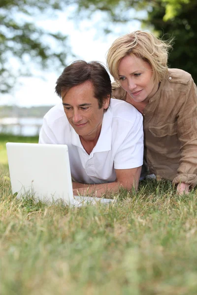 Ζευγάρι χρησιμοποιώντας φορητό υπολογιστή τους σε ένα δημόσιο πάρκο — Φωτογραφία Αρχείου
