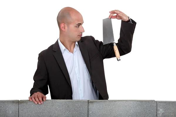 A businessman looking at a trowel. — Stock Photo, Image