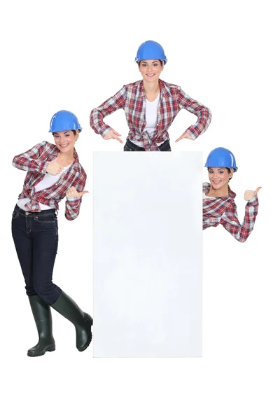 Costruttore femminile in piedi con poster in bianco — Foto Stock
