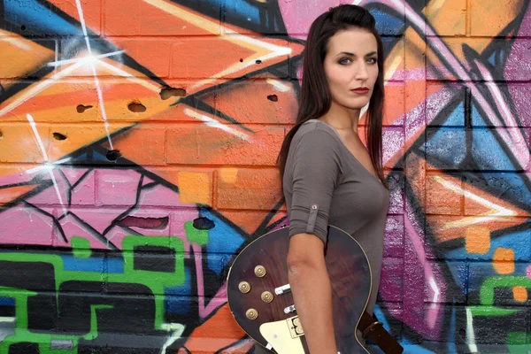Κορίτσι με κιθάρα μπροστά από το χρωματισμένο τοίχο — Φωτογραφία Αρχείου