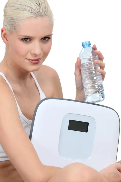 Молода жінка з пляшкою води і парою ваг — стокове фото