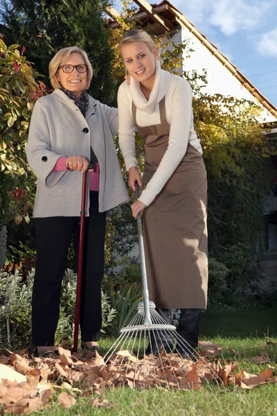 Jovem mulher ajudando um idoso com seu jardim — Fotografia de Stock