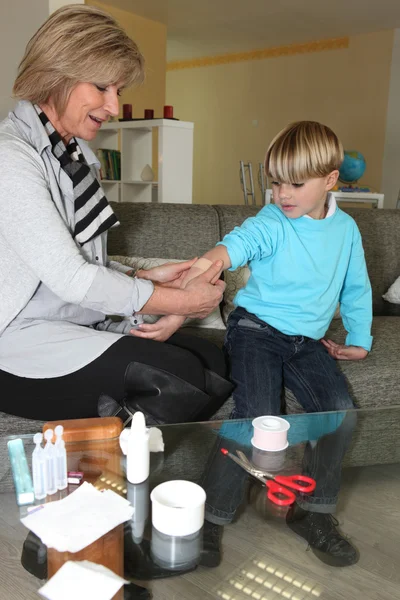 Жінка наклеює штукатурку на руку дитини — стокове фото