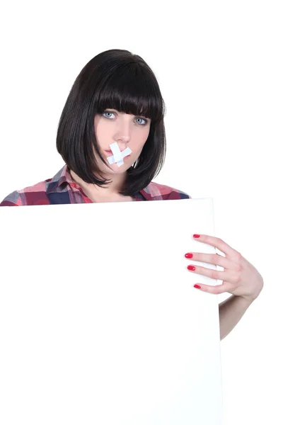 Woman with bandage across her mouth and a board left blank for your message — Stock Photo, Image