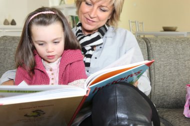 Grandmother reading a story to her granddaughter clipart