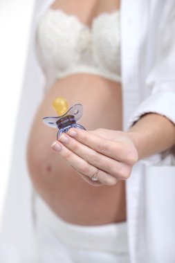 Pregnant woman holding a pacifier clipart