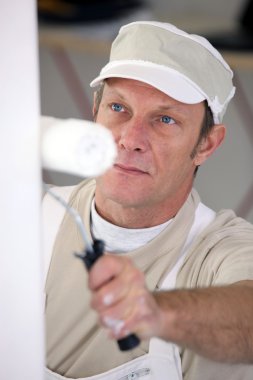 Closeup picture of mature painter holding roller clipart