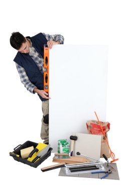 Tiler using spirit-level on blank poster clipart