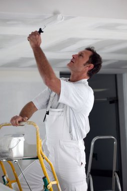 Painter using roller to coat ceiling clipart