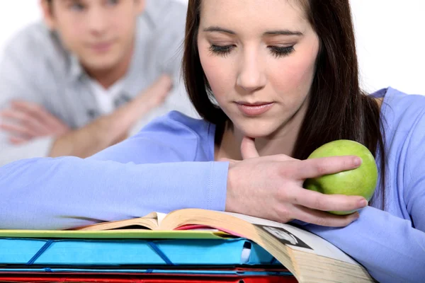 Student eating apple whilst reading — Stock Photo, Image
