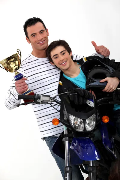 Motorcycle racers holding their trophy — Stock Photo, Image