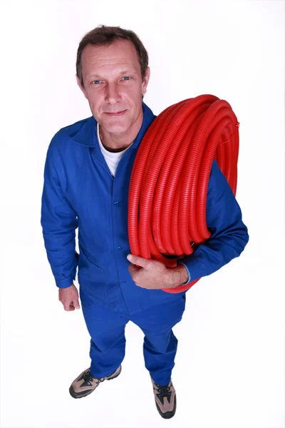 Loodgieter met grote reel van rode flexibele pijp — Stockfoto