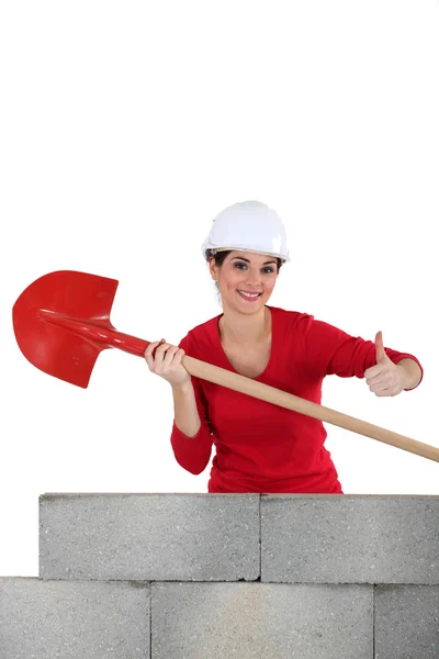 Hantverkerska innehar en spade och göra tummen upp skylt — Stockfoto
