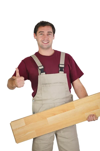Hantverkare innehar en parkett planka och göra tummen upp skylt — Stockfoto