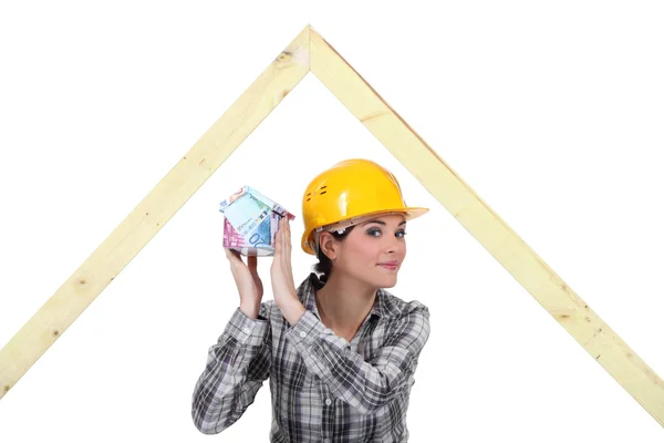 Mischievous female joiner holding miniature house — Stock Photo, Image