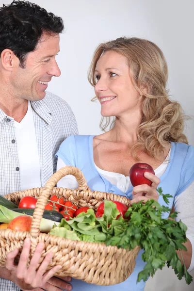 Пара дивиться один одному в очі з овочевим кошиком . — стокове фото