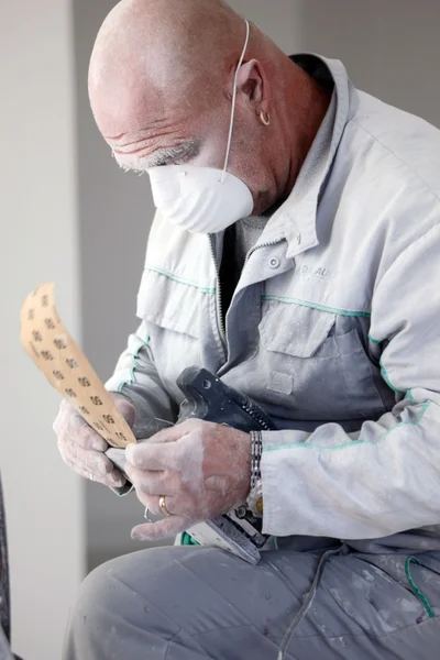Decorator fitting sandpaper onto an electric sander — Stock Photo, Image