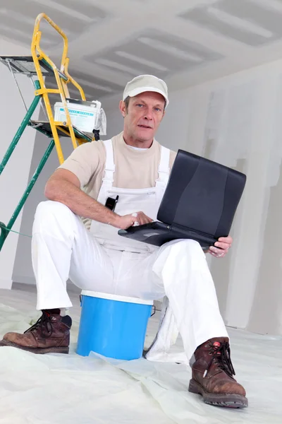 Pintor com laptop sentado com escada — Fotografia de Stock
